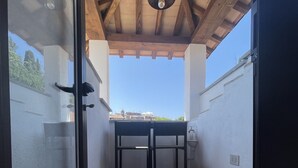 Un patio couvert avec une table et des chaises, un ventilateur de plafond et une vue sur les bâtiments en arrière-plan.
