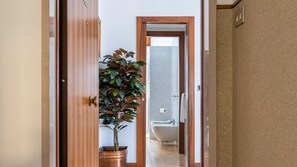 A hallway leading to a bathroom with a bathtub and a potted plant. - Appartamento  Marullina (Verona)