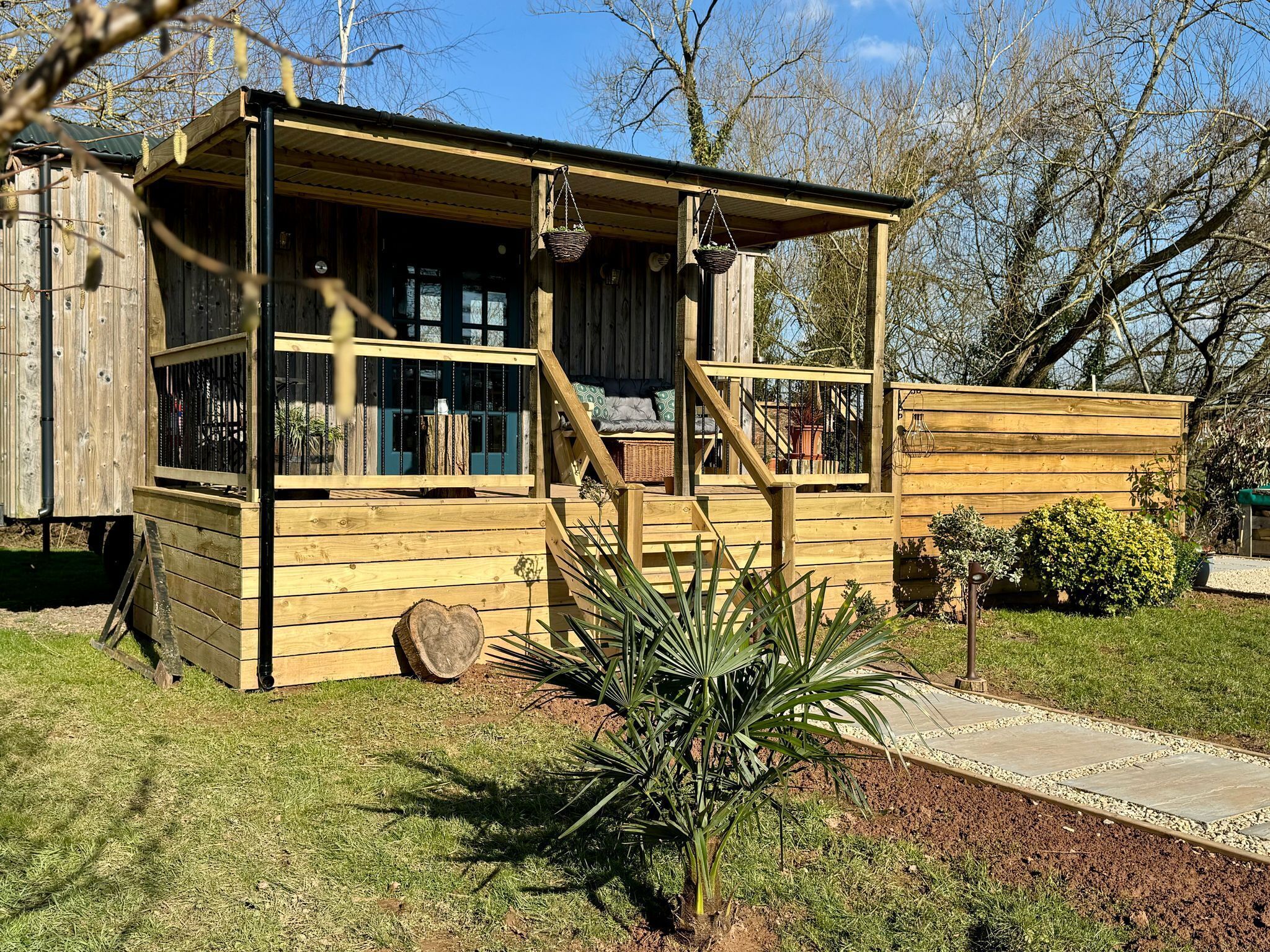 A wooden cabin with a porch, large windows, and a small garden area.