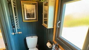 Ett litet badrum med toalett, handfat och fönster.