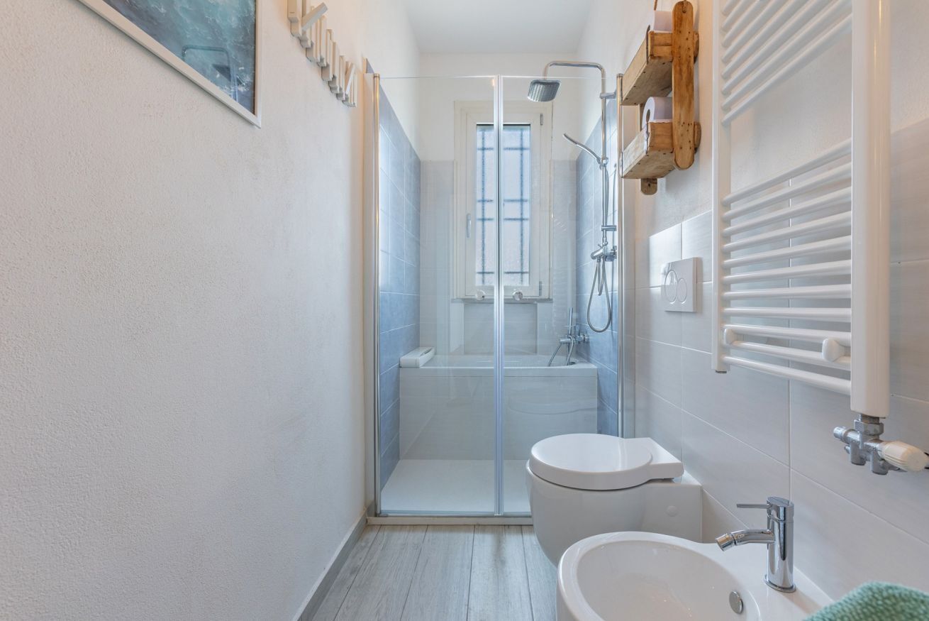 A modern bathroom with a glass shower enclosure, a toilet, and a sink.