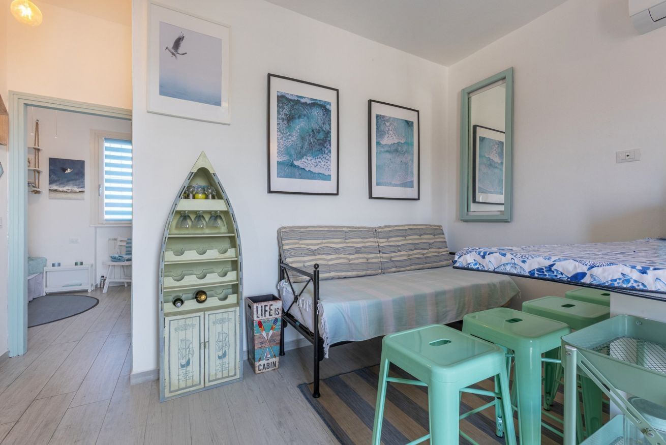 Een slaapkamer met een bed, een groen kastje, een bank en een kleine tafel.