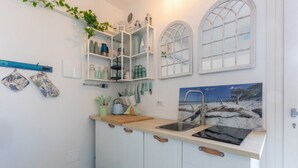Eine Küche mit weißen Schränken, einer Holzauskładung, einem Spülbecken und einem Fenster mit Blick auf einen Strand.