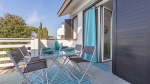 Ein Balkon mit Esstisch, Stühlen und einer blau gestreiften Matte.