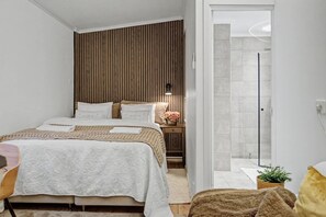 Un dormitorio moderno con cama, mesita de noche y vistas al baño.