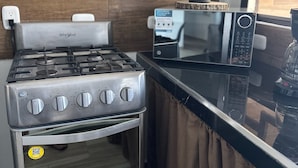 Una cocina con estufa a gas Whirlpool, un microondas y una planta en maceta sobre la encimera.