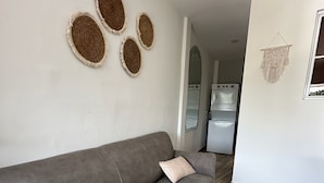Una sala de estar moderna con un sofá gris, dos tapices tejidos decorativos y un tapiz de macramé.