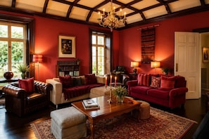 A room with a fireplace, leather sofas, a coffee table, and a chandelier.