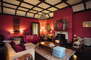 A cozy living room with a fireplace, plush seating, and a chandelier.
