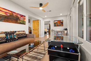 A living room with a sofa, coffee table, and a foosball table. - Gorgeous Designer Home, Sedona Red Rock Basin Views, Outdoor Living Entertainment Patio w/ Firepit & BBQ! The Den - S079 (Sedona)