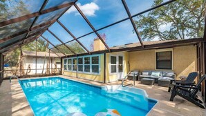 A swimming pool with a glass enclosure, outdoor seating, and a view of the surrounding area. - Aqua Queen - Pool 3BR (St. Augustine)