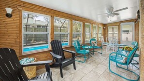 A sunroom with wooden walls, large windows, and a ceiling fan. - Aqua Queen - Pool 3BR (St. Augustine)