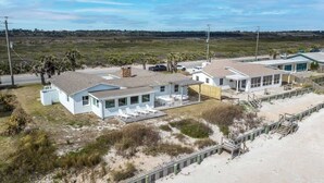A beachfront property with a house, a covered patio, and a sandy beach area. - Blue Horizon House - 3BR Oceanfront (Ponte Vedra Beach)