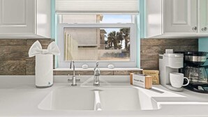A modern kitchen with a sink, faucet, window with blinds, and coffee maker. - Blue Horizon House - 3BR Oceanfront (Ponte Vedra Beach)