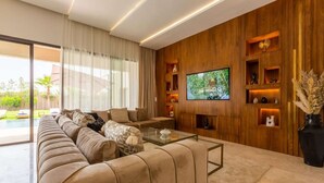 Ein modernes Wohnzimmer mit einem großen Sofa, einem Couchtisch und einem an einer Holzwand montierten Fernseher.