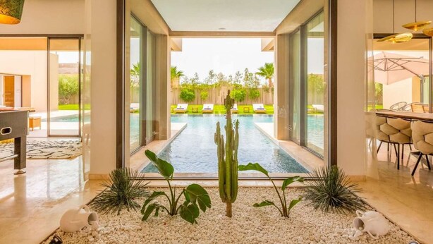 Ein modernes Interieur mit Glastür zum Poolbereich, gestaltet im minimalistischen Stil, mit einer Kakteenpflanze und Kies.