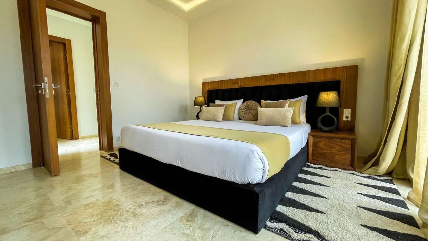 Une chambre à coucher avec un lit, des tables de chevet, une lampe et une porte.