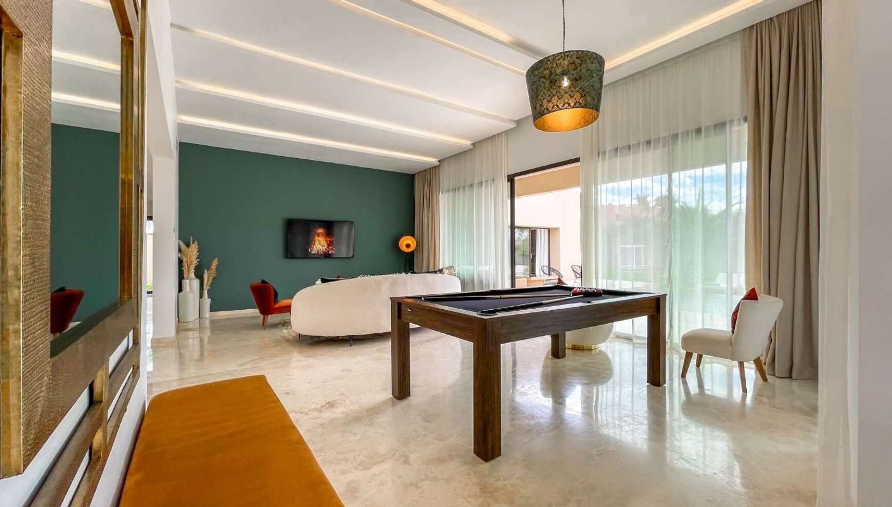Un salon moderne doté d’une table de billard, de sièges confortables et d’une grande fenêtre laissant entrer la lumière naturelle.