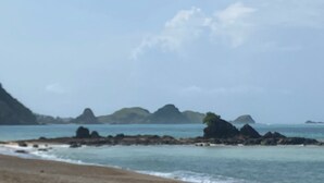 A beach with rocky outcrops and distant mountains. - Roh Villas Kuta Lombok (Kuta)