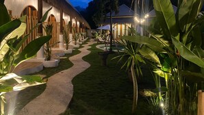 A resort with thatched-roof buildings, a winding pathway, and lush tropical plants. - Roh Villas Kuta Lombok (Kuta)