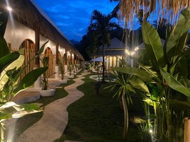 Um resort com edifícios de telhado de palha, um caminho sinuoso e exuberante vegetação tropical.
