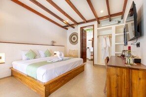A bedroom with a wooden bed frame, a desk with a chair, a TV mounted on the wall, and a wardrobe.