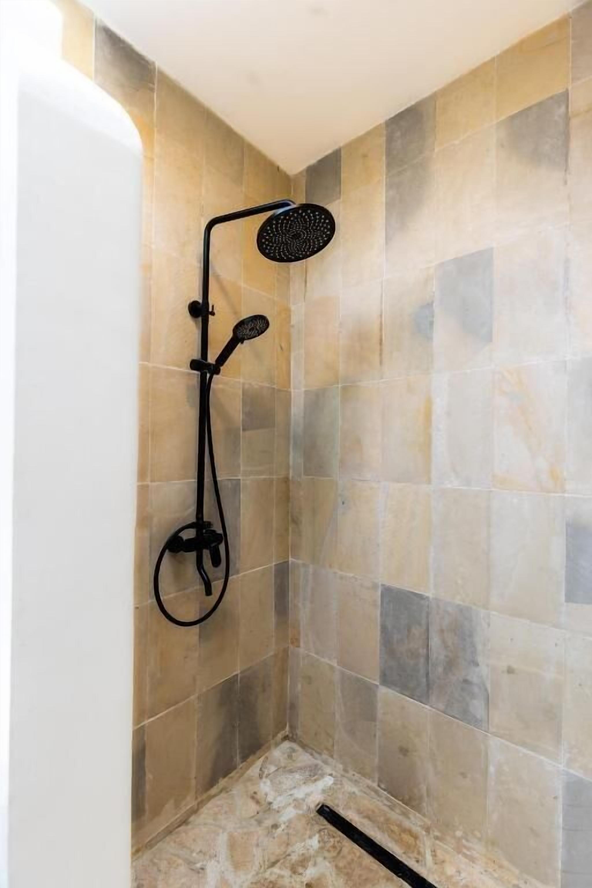 Een douche met een handdouche en een wandmengkraan.