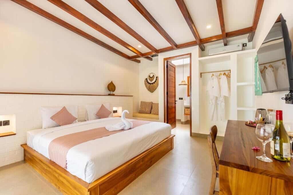 Una habitación de hotel con un marco de cama de madera, una mesa de comedor de madera y un televisor montado en la pared.
