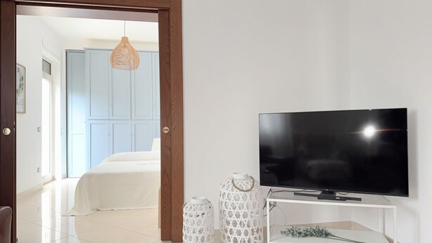 Ein Schlafzimmer mit einem Bett, einem Fernseher auf einem Schrank und zwei dekorativen Laternen.