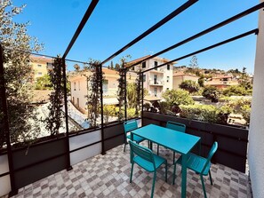 Ein Balkon mit kariertem Boden, einem Tisch und Stühlen.