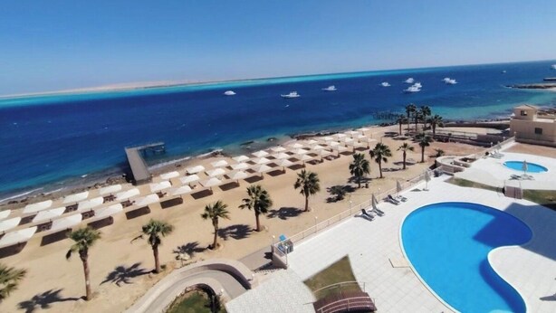 Un resort con piscina, ombrelloni da spiaggia e vista sull'oceano.