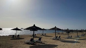 Una spiaggia con ombrelloni e lettini.