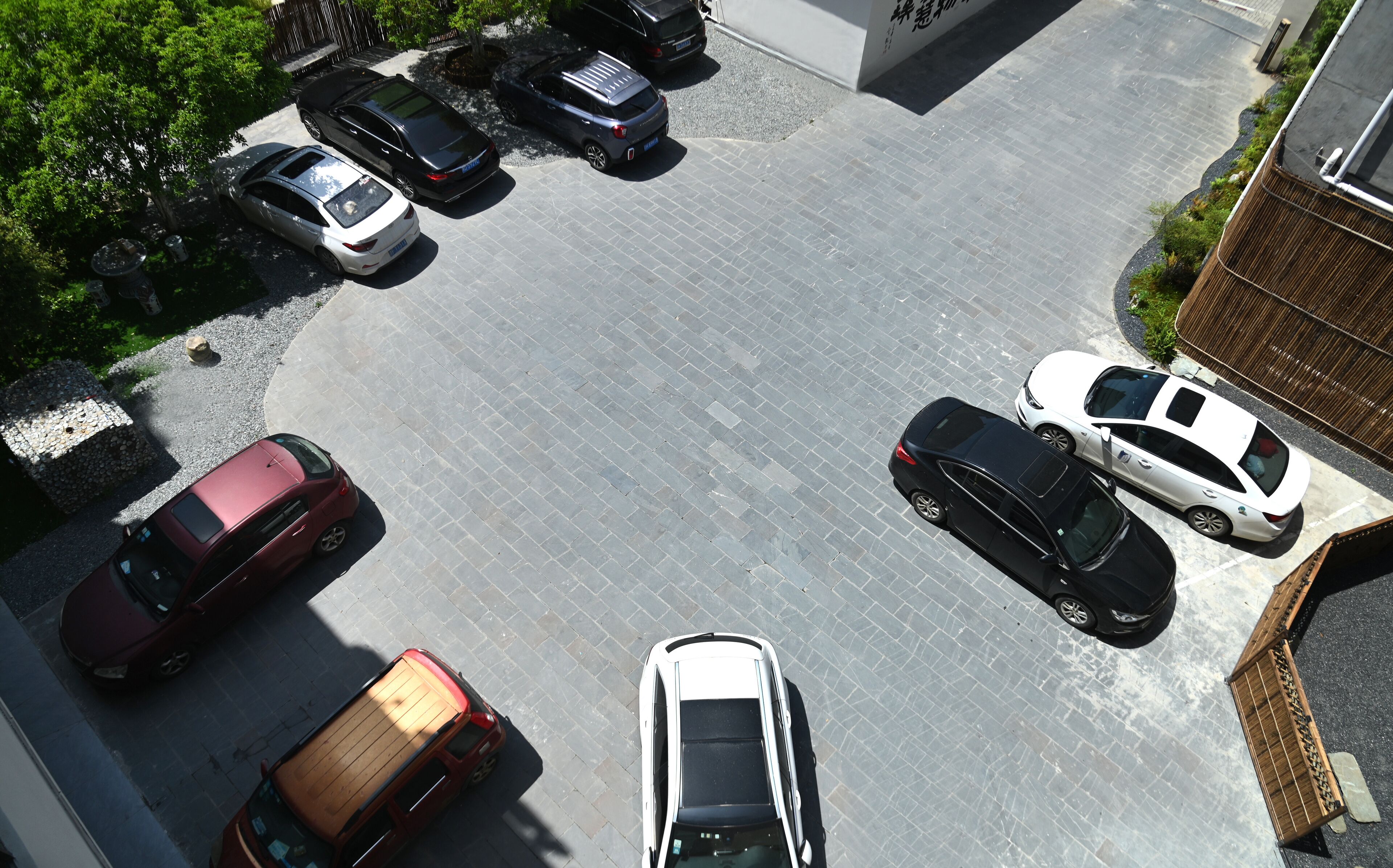 A parking lot with multiple cars, a wooden structure, and a building with a sign.