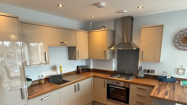 A modern kitchen with white cabinets, a gas stove, and a stainless steel range hood. - Christchurch Apartment, Great Location With Parking (Christchurch)