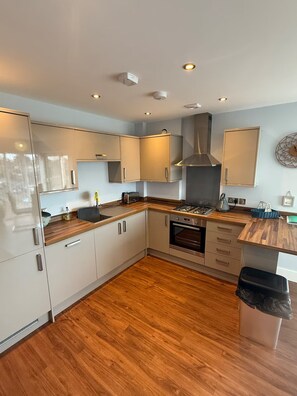A modern kitchen with white cabinets, a gas stove, and a stainless steel range hood. - Christchurch Apartment, Great Location With Parking (Christchurch)