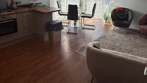 A modern kitchen with a dining area, a living room with a sofa, and a balcony with a view. - Christchurch Apartment, Great Location With Parking (Christchurch)