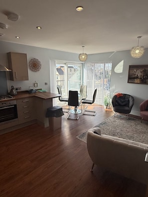 Una cocina moderna con comedor, una sala de estar con sofá, y un balcón con vistas.