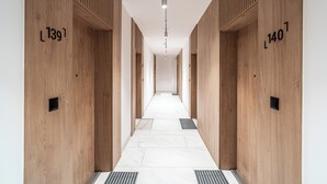 A modern hallway with wooden paneling and numbered doors, leading to individual rooms. - RentPlanet - Apartament Przemysłowa (Katowice)
