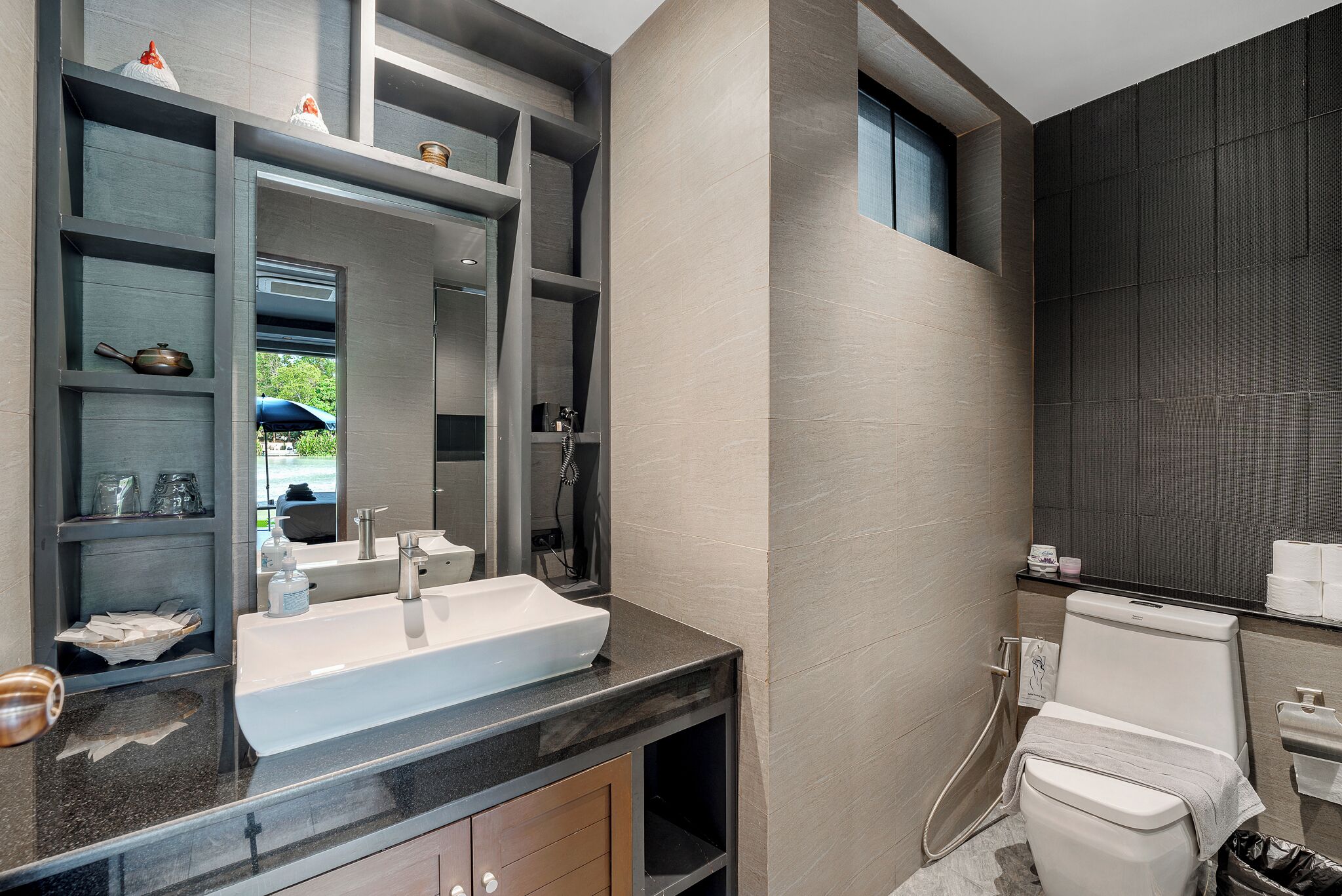 Un baño moderno con lavamanos amplio, espejo y retrete.