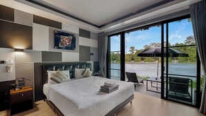 Ein modernes Hotelzimmer mit einem großen Bett, einem Nachttisch, einem Schreibtisch und Seeblick durch große Fenster.