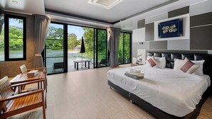 Ein modernes Hotelzimmer mit einem großen Bett, einer Essecke und Blick auf ein Gewässer.