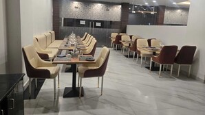 Un espace de restauration moderne avec de longues tables et des chaises, un sol en marbre et un mur en pierre sur lequel est affiché le menu.