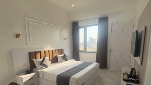 Une chambre d’hôtel moderne dotée d’un grand lit, d’un téléviseur à écran plat, d’un bureau avec une chaise et d’une fenêtre avec des rideaux.