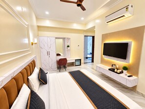 Een moderne slaapkamer met een bed, bureau, televisie en airconditioning.