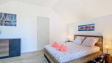 Ein Schlafzimmer mit einem Bett, einem Nachttisch, einer Lampe und einem Bild an der Wand.