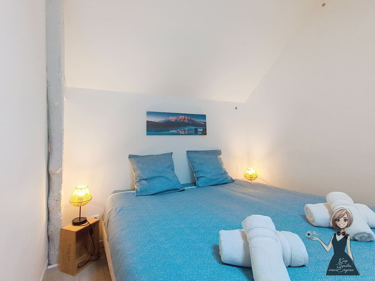 Une chambre à coucher avec un lit, deux oreillers, une table de chevet avec une lampe et une serviette sur le sol.