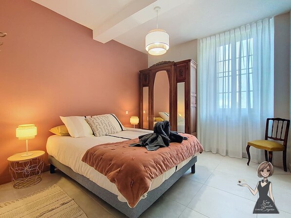Une chambre à coucher avec un lit, des lampes de chevet, une chaise et un miroir.