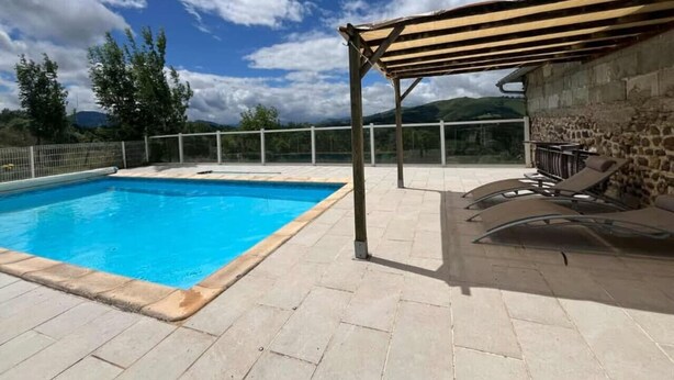 A swimming pool with a pergola and lounge chairs, surrounded by a stone wall and a view of the mountains. - Gîte Cazette, un coin de Paradis au cœur du Béarn. (Ance Féas)
