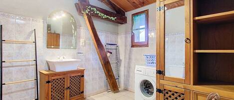 Un baño con tocador de madera, lavadora y perchero para toallas.