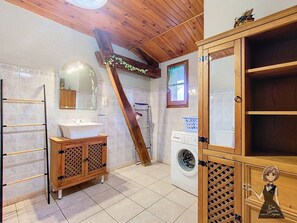 Une salle de bain avec un meuble-lavabo en bois, un lave-linge et un porte-serviettes.